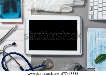 High angle shot of tablet and medical items on gray surface