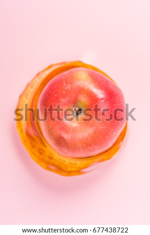Measuring tape around apple on pink background. Tips nutritionists doctors. Dietetic foods that nutritionists advise for a health. Dietary food and proper nutrition for athletes.