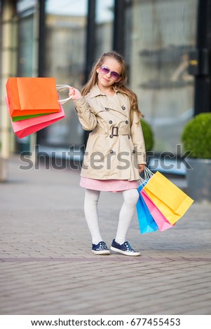 Little fashion girl on shopping outdoors in the city