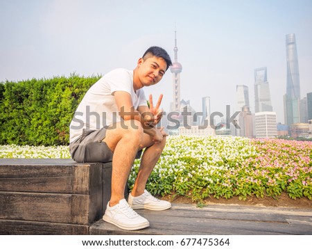 Outdoor portrait of young Asian man with shanghai bund skyline background.