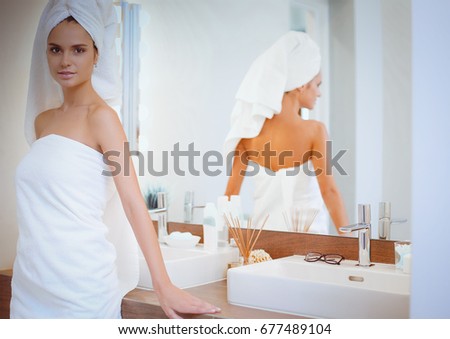 Young attractive woman standing in front of bathroom mirror