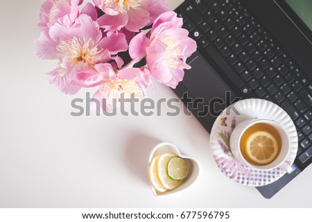 Bouquet of peonies, tea with lemon, a laptop, photo in gentle colors. Good morning. Have a nice day! Place for text