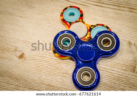 Blue fidget SPINNER stress relieving toy on wood background.