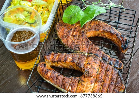 Grilled salmon steak. Glas with beer. Cabbage salad. Picnic in nature Royalty-Free Stock Photo #677738665