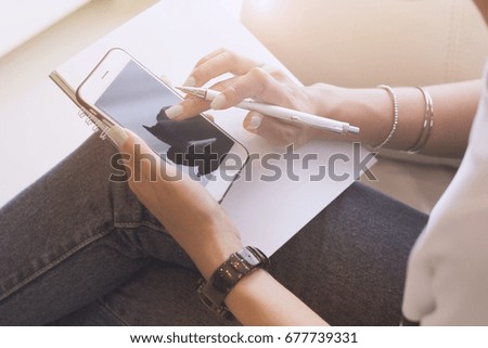 women using smart phone with holding pen ad book in the working room