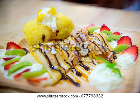 Kiwi and strawberry ice crepe, served on wood plate. sweet and soft. image for background, object and copy space.high calories. diet don't eat concept