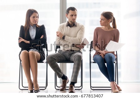 Male and female ambitious job seekers waiting for interview, looking at each other with hate and dislike, feeling jealous envious, rivalry and internal competition, get position and sidestep rivals Royalty-Free Stock Photo #677813407