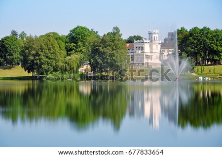 The city museum in Druskininkai reflected in a lake with a fountain in the summer. Lithuania. Royalty-Free Stock Photo #677833654