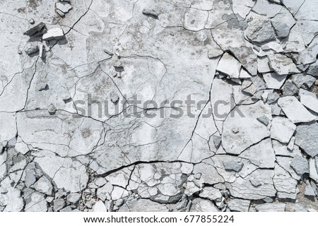 Cracked concrete texture background. Grey surface with cracks close up. A lot of pieces of splintered plaster. Abstract concept of split, dissent, disagreement, discord. Sunny day with shadows. Royalty-Free Stock Photo #677855224