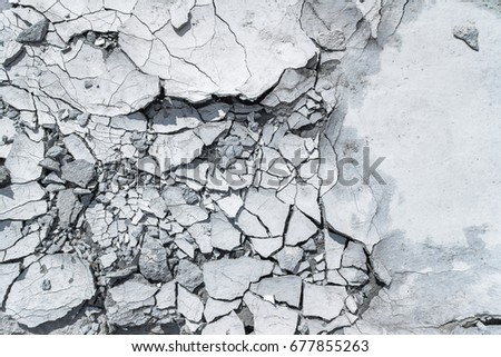 Cracked concrete texture background. Grey surface with cracks close up. A lot of pieces of splintered plaster. Abstract concept of split, dissent, disagreement, discord. Sunny day with shadows. Royalty-Free Stock Photo #677855263