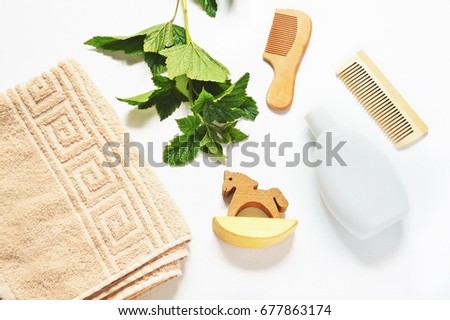 Shampoo bottle, wooden comb, toy horse, cotton beige towel and green currant leaves. Natural organic cosmetics for hair care. Bath products, bathroom set