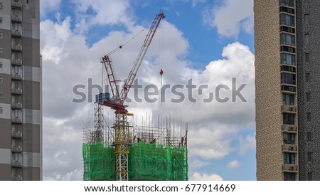 Building under construction and Tower Crane on Blue sky background.