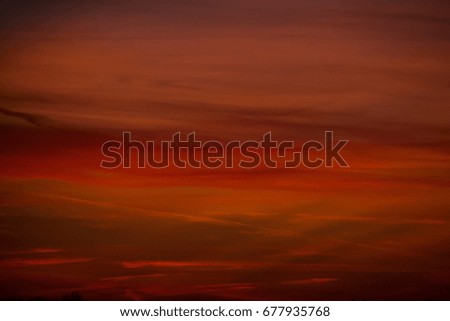 Colorful evening sky with red cloudscape and stripes illuminated by the sun after sunset
