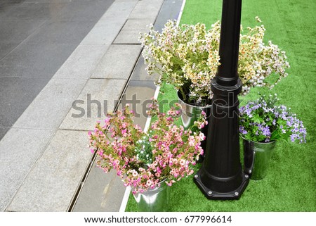 Beautiful street decorated with buckets of artificial colorful flowers underneath black lamp post