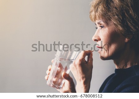 Adult woman with a pill and a glass of water / healthcare concept Royalty-Free Stock Photo #678008512