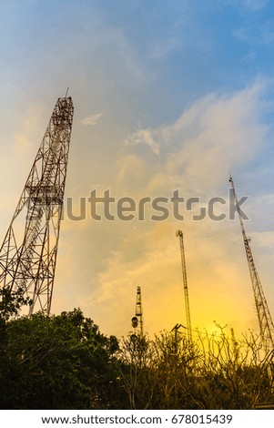 Telecommunication towers on the summit of the hill under cloudy blue sky and covered with colorful fall forest.