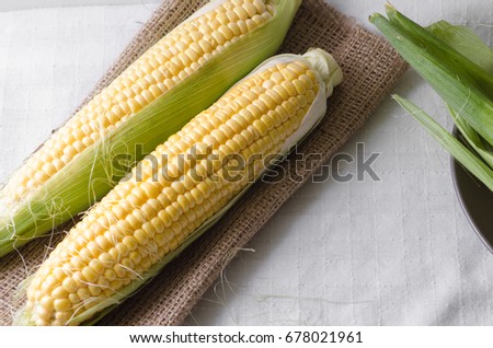 Raw corn with leaves on a sackcloth in rustic style. Close-up side view Royalty-Free Stock Photo #678021961