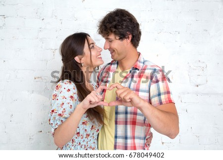 Couple in love gesturing heart with fingers. 