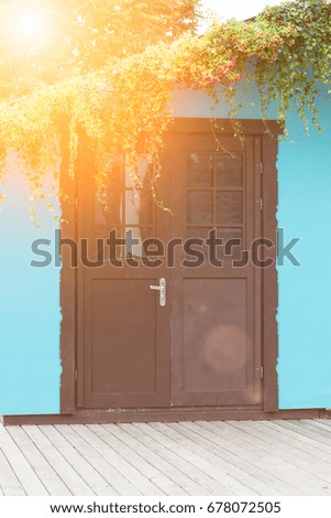 View from the front of the wooden brown door on the blue house with a window