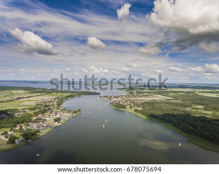 Aerial view of green islands and clouds at summer sunny morning. Masurian Lake District  in Poland. Wonders of the world from above. Yachts sailing in the lake.