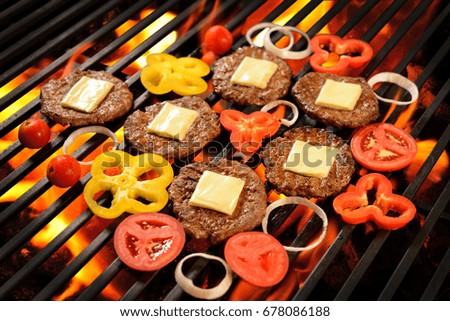 Grilled meat/burger with cheese and vegetable on the flaming grill
