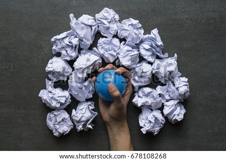 Hand of a woman squeezing a stress ball with crumpled paper