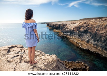 Young woman enjoying beautiful sea view on Greco cape in Cyprus. Back view