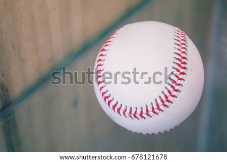 A close up image of an old used baseball on a glass background.