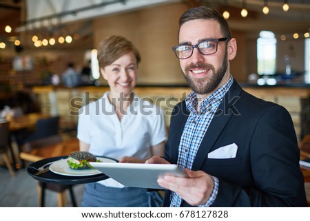 Elegant trader with touchpad and waitress with sandwich on tray