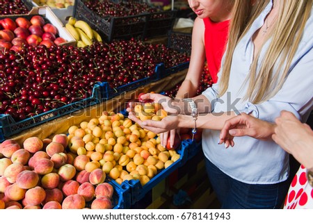Three young women at grocery market. Women choose fruit. The middle plan. Focus on the hands.