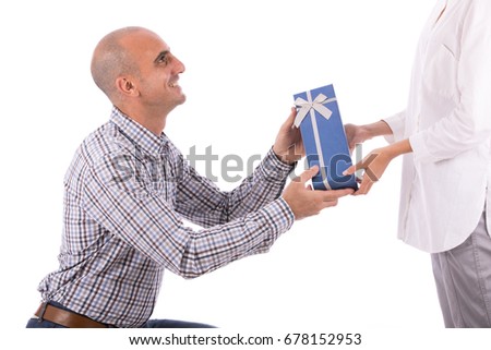 Mature bald man smiling and giving a blue gift box to someone, guy wearing caro shirt and jeans, isolated on white background