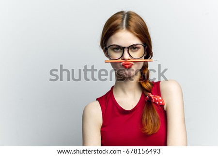 Woman in glasses holds a pencil on a light background