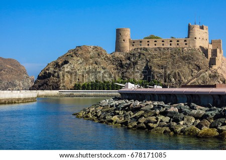ancient stone fortress at seashore with blue sea and big rock at foreground and blue sky at background