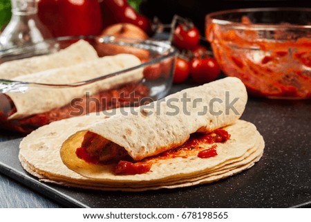 Preparation traditional mexican enchiladas with chicken meat, spicy tomato sauce and cheese. Mexican cuisine.