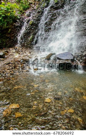  Waterfall.Water falls from the rocks in the mountain river with transparent water,green forest.Carpathians           