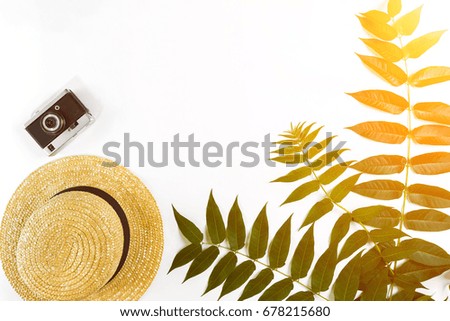 Straw hat with green leaves and old camera on white background, Summer background. Top view. Sun flare