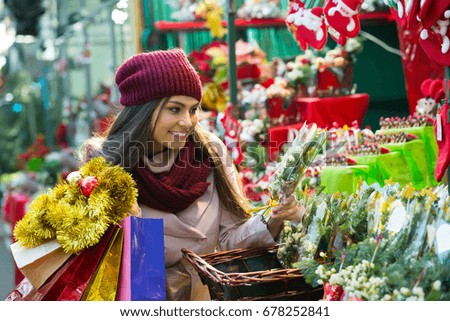 Joyful smiling girl buying home decorations at Christmas market
