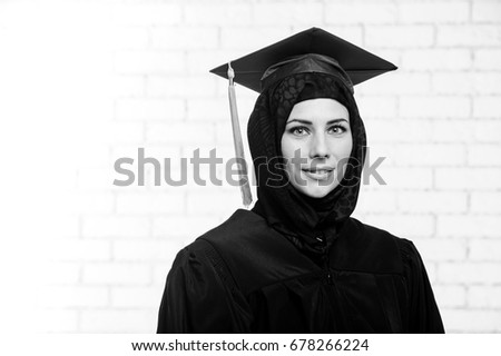 Happy graduate female muslim student poses indoors.Black and white picture.
