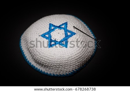 Knitted kippah with blue David star on black background close up. Seder concept. Royalty-Free Stock Photo #678268738