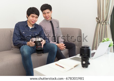 Freelance photographer and desginer looking on dslr camera working together at home office editing retouch photos on computer laptop.