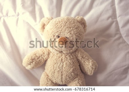 Teddy bear with depression laying on the bed.
