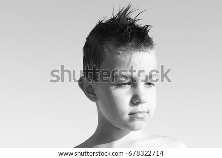black and white portrait of summer, the boy's face with drops of water on the beach with a hair Iroquois