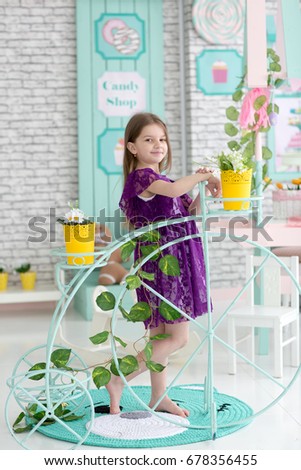 Sweet little dark hair girl in purple dress in studio