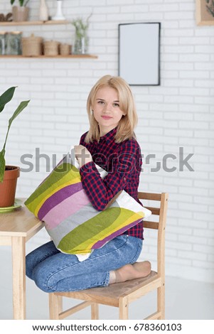 Beautiful blond woman with cushion and phone in studio