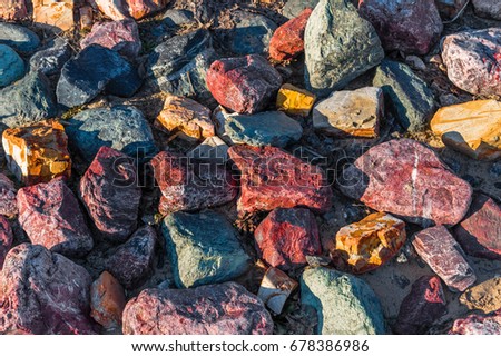 Big colorful stones. Color rocks texture background. Stone surface. Abstract pattern textured of many granite rough stones. Filled frame picture. Pile of boulders piled in heap. Sunny with shadows