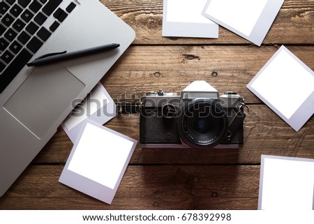 Vintage photo camera. Blank photo frames. Old photographs of paper, on wooden background, next to modern computer