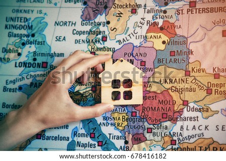 hand holding symbol of home on world map background