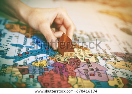 hand holding symbol of home on world map