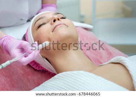 Woman getting face peeling procedure in a beauty SPA salon. Rejuvenating facial gas liquid treatment.  Hydro air skin cleansing operation. Close up, selective focus. Royalty-Free Stock Photo #678446065