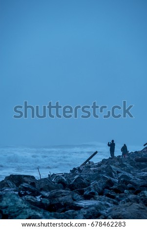 People on a jetty taking pictures during stormy conditions